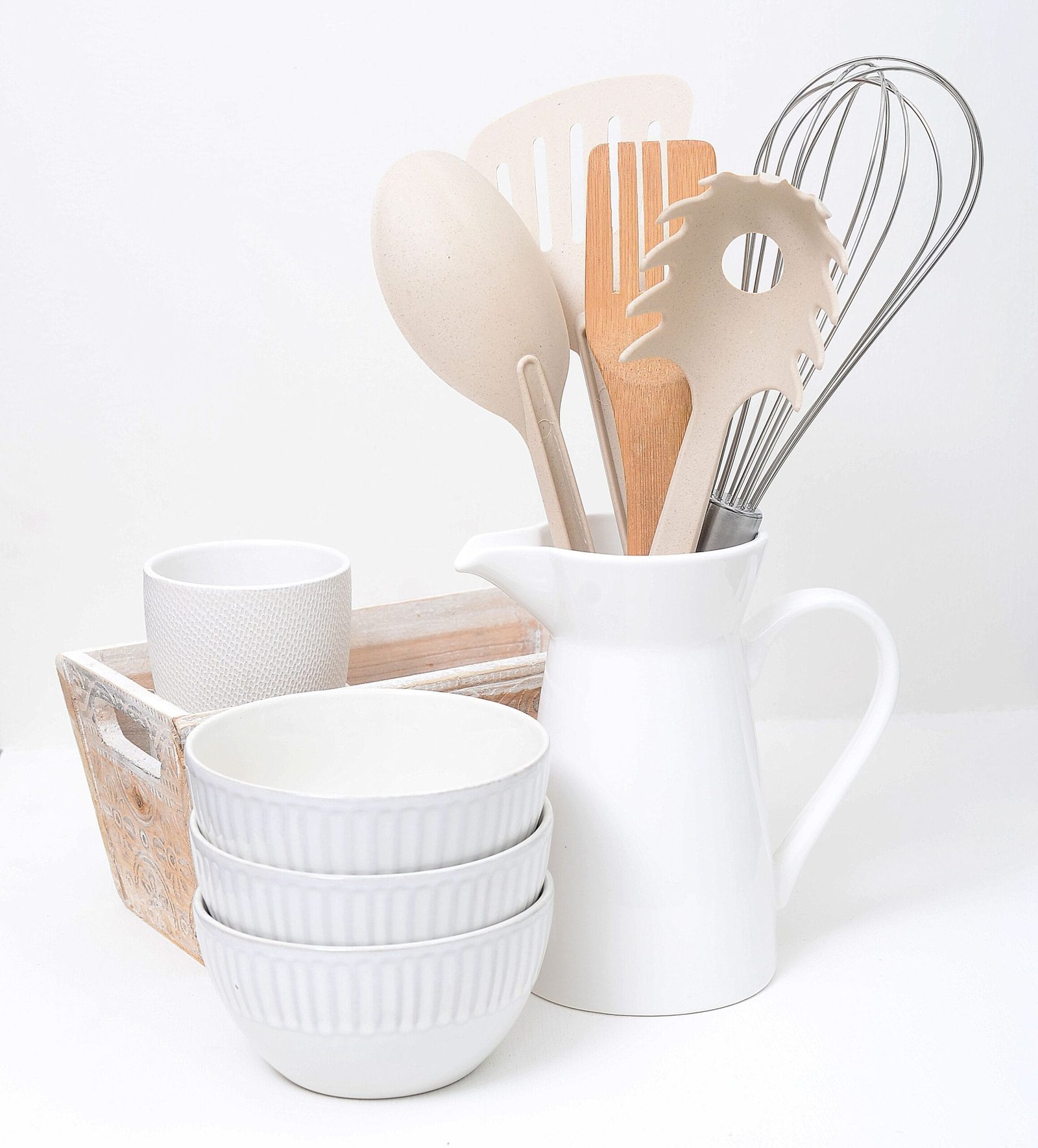 Simple white kitchenware set with wooden utensils in a minimalist style.